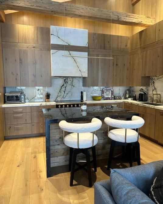 A kitchen with wooden cabinets and marble counter tops