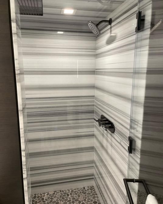 A shower with a striped wall and a shower head.