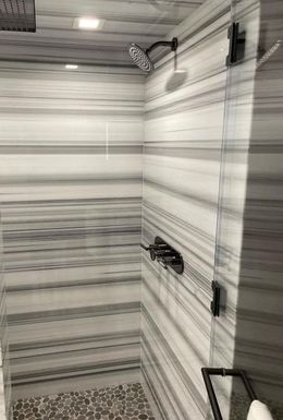 A shower with a striped wall and a shower head.