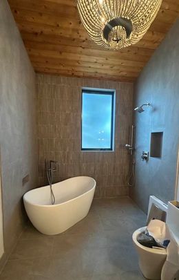 A bathroom with a bathtub , toilet and shower.