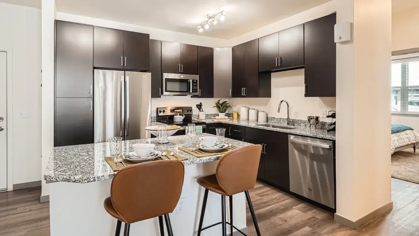 Modern kitchen in an apartment with granite countertops and stainless steel appliances.