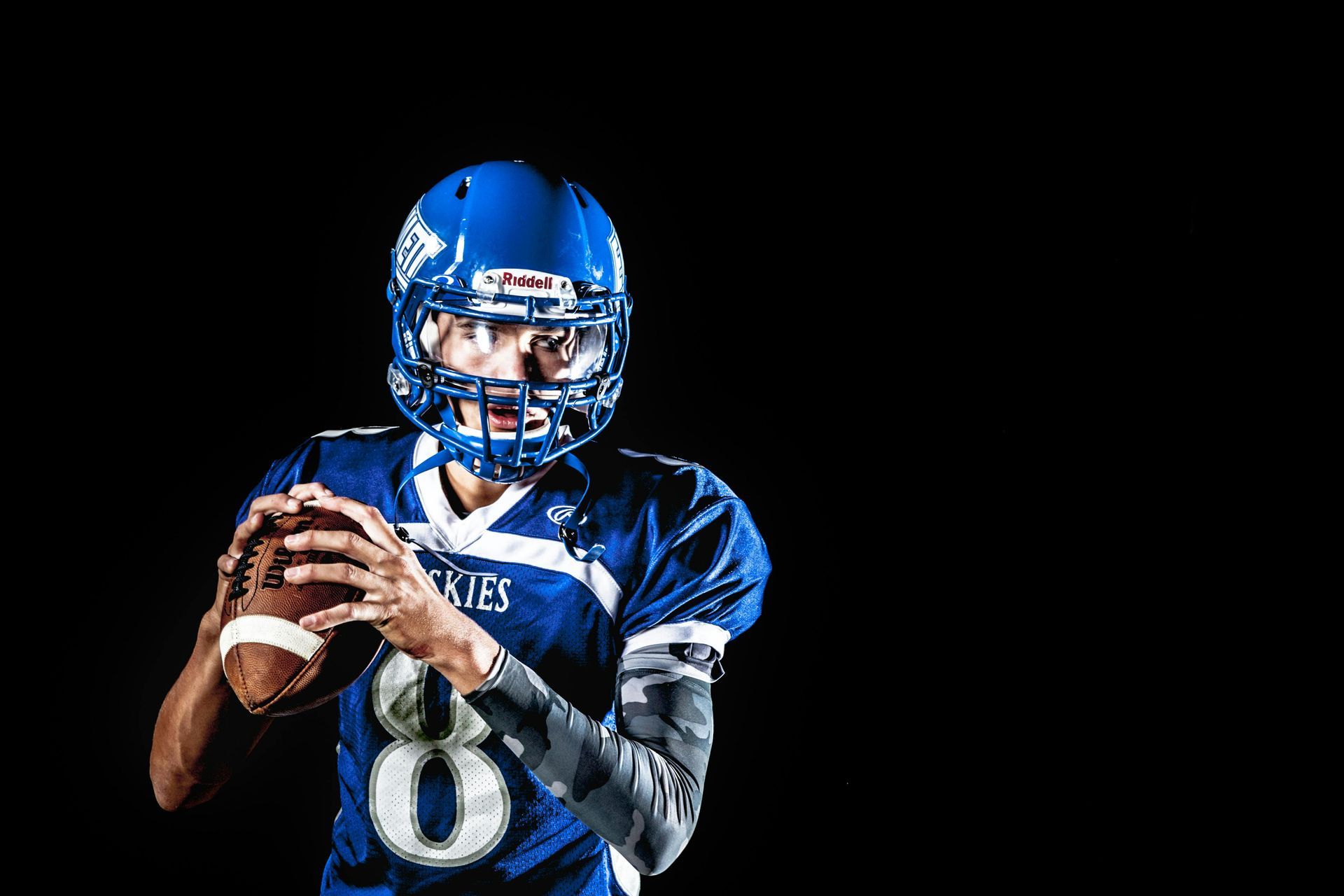 A football player in a blue uniform is holding a football in his hands.