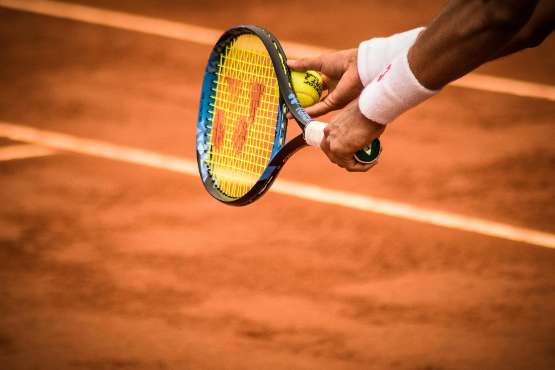 Una persona sostiene una raqueta de tenis y una pelota de tenis en una cancha de tenis.