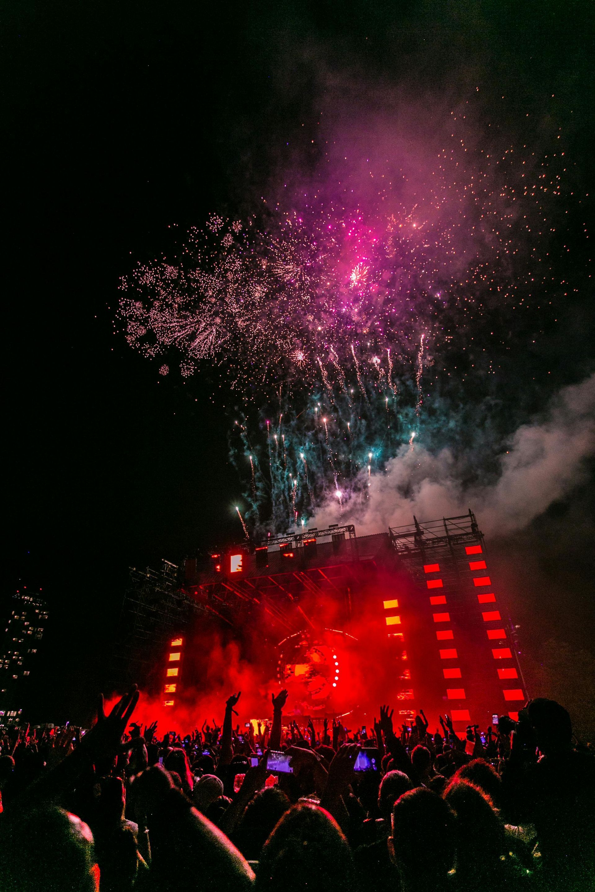 Una multitud de personas viendo fuegos artificiales en un concierto.