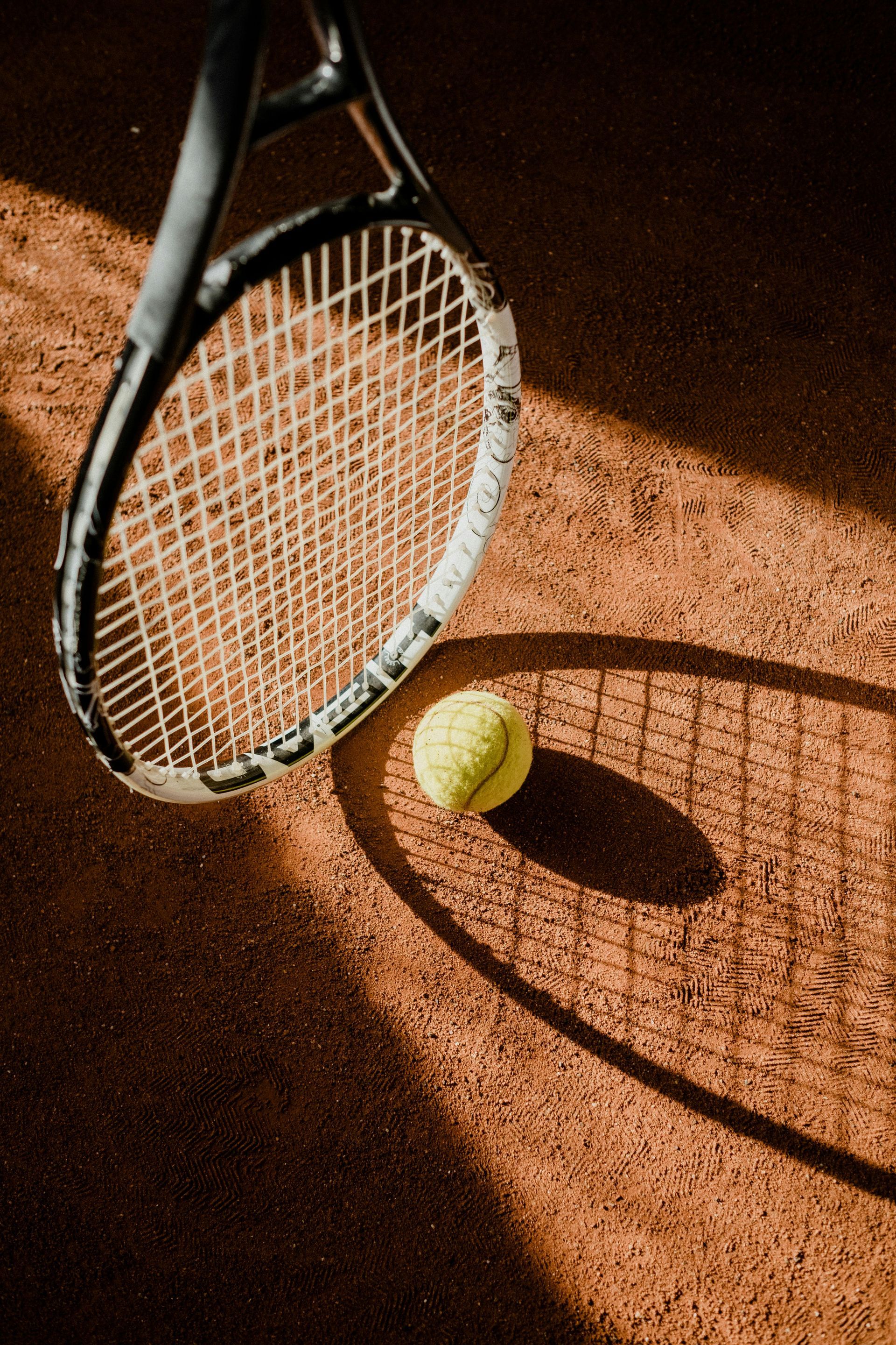 Una raqueta de tenis y una pelota están en una cancha de tenis.