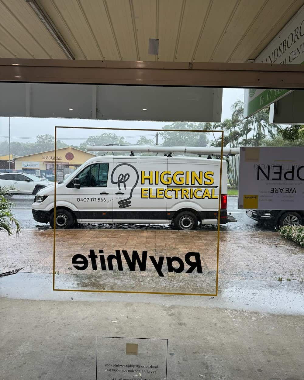 A Higgins Electrical Van Is Parked in The Rain in Front of A Building — Higgins Electrical in Beerwah, QLD