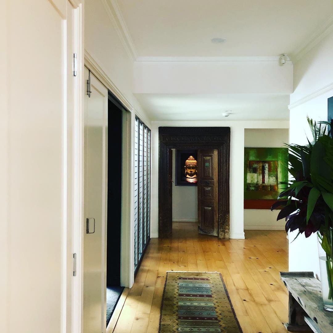 Hallway with hardwood floors, rug, sliding doors, art, and a decorative doorway — Higgins Electrical in Beerwah, QLD