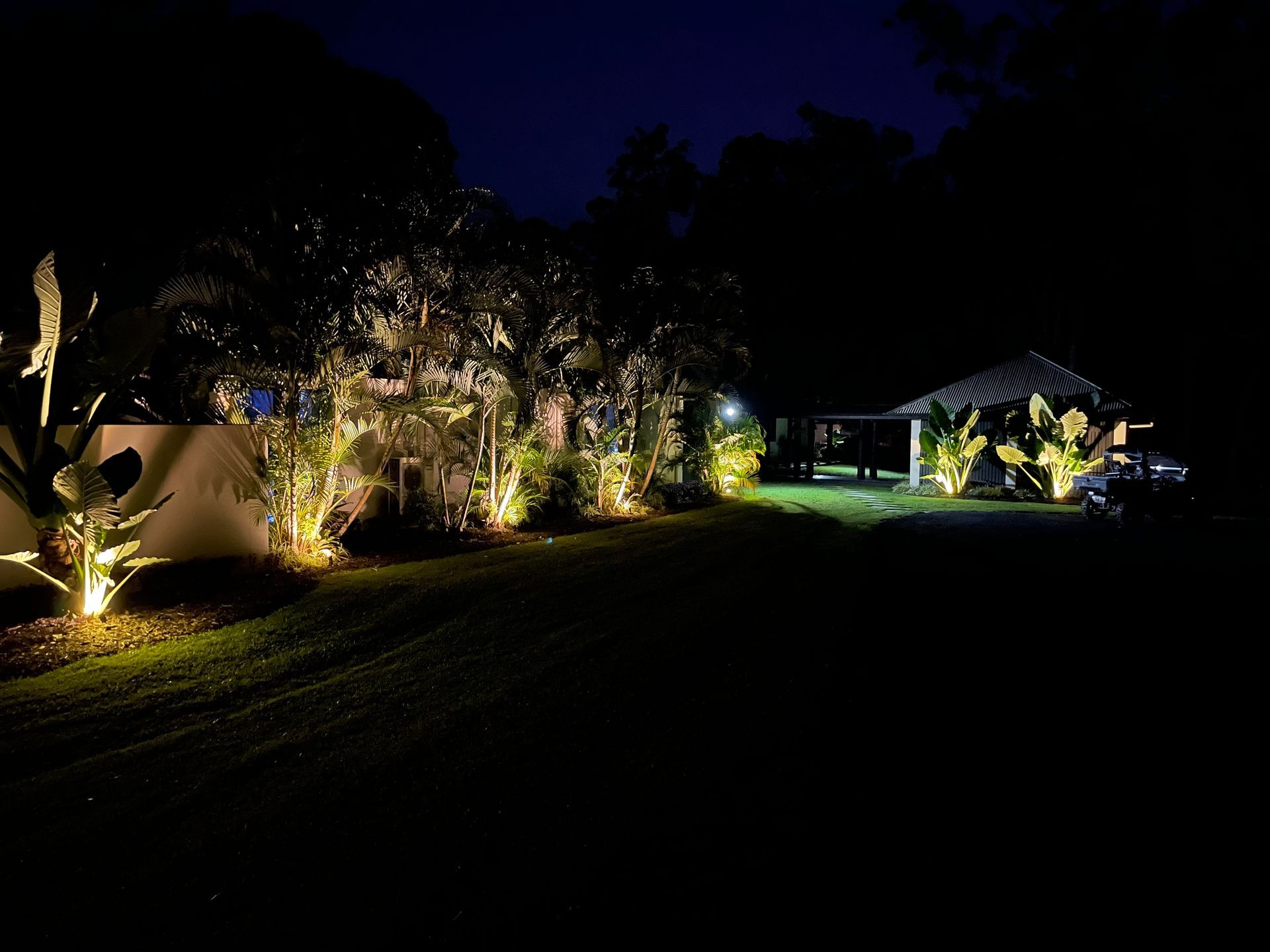 A House at Night, Lit With Yellow Lights, With a Carport and Palm Trees — Higgins Electrical in Bribie  Island, QLD