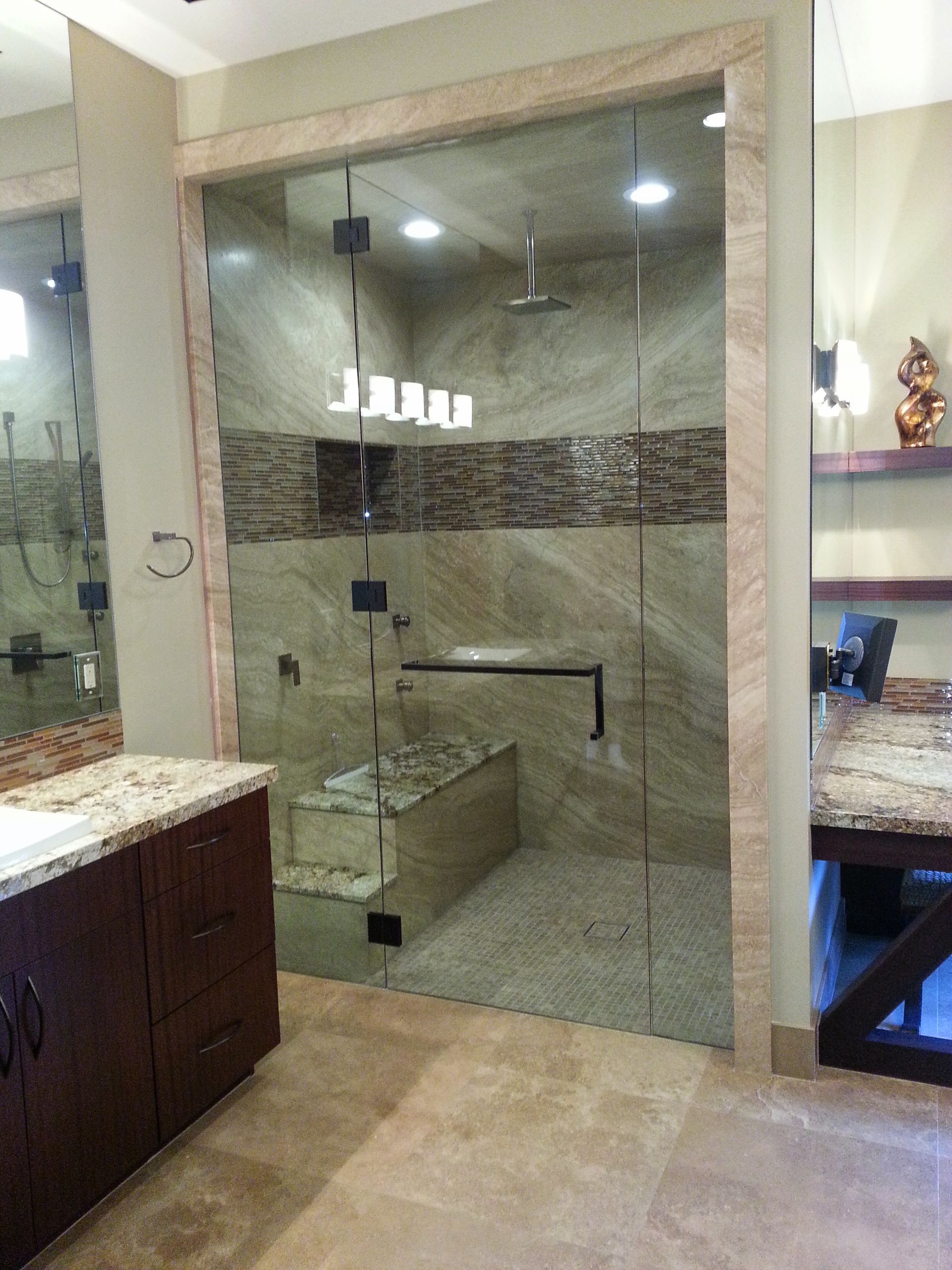 A bathroom with a walk in shower with a glass door