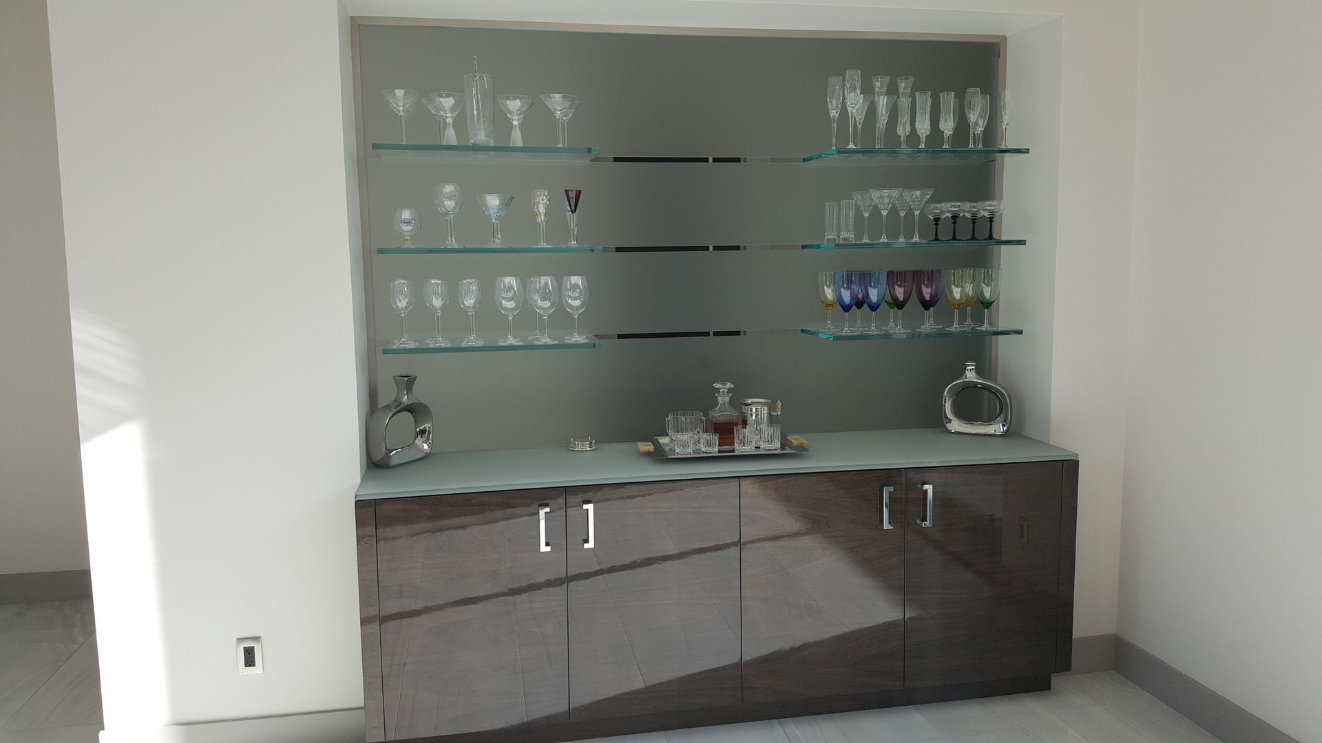 A room with a bar and shelves filled with wine glasses.