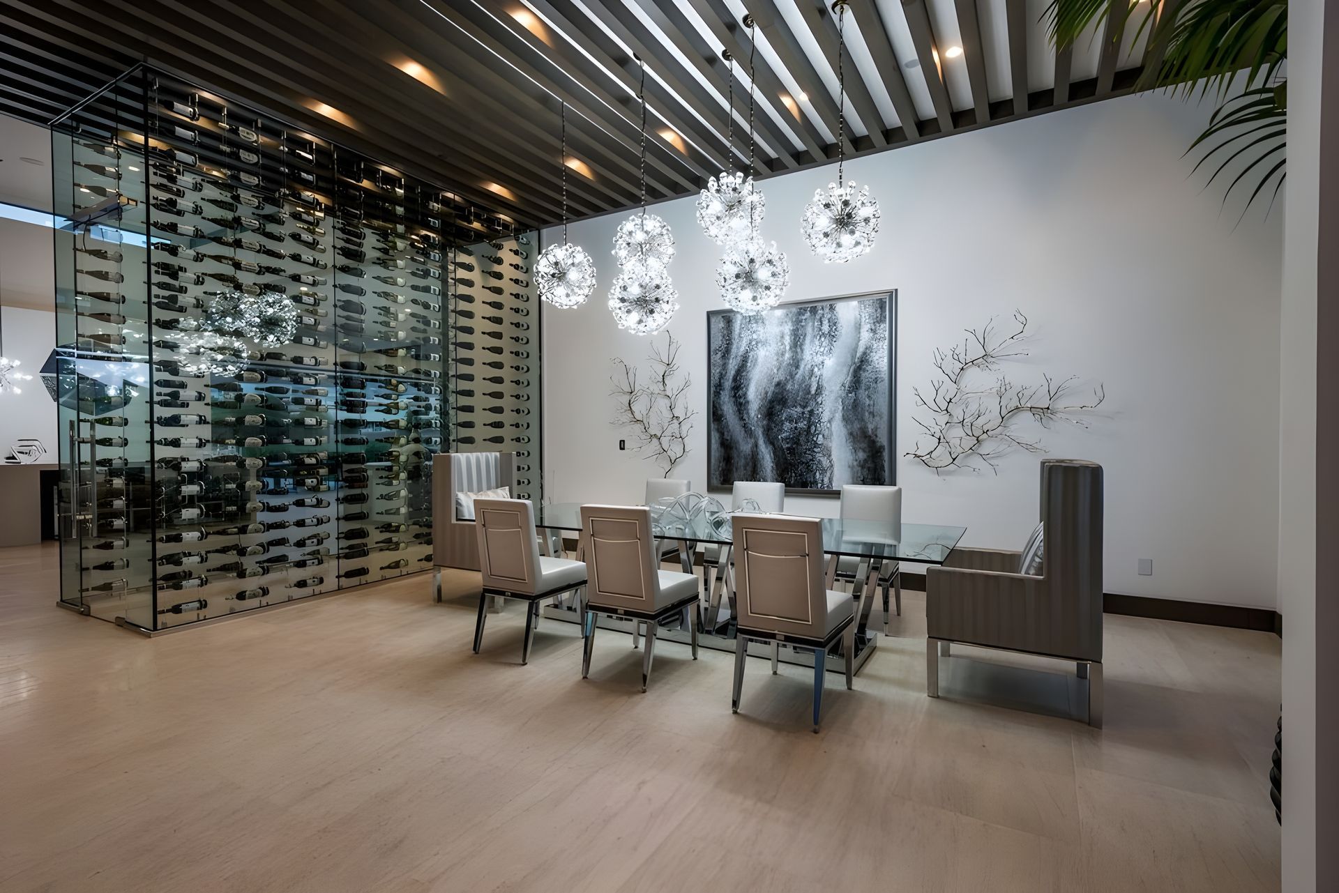 A dining room with a glass table and chairs and a wine cellar behind it.