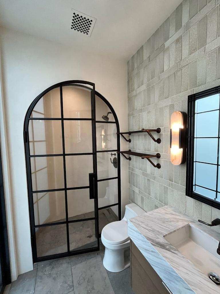 A bathroom with a toilet , sink , shower and mirror.