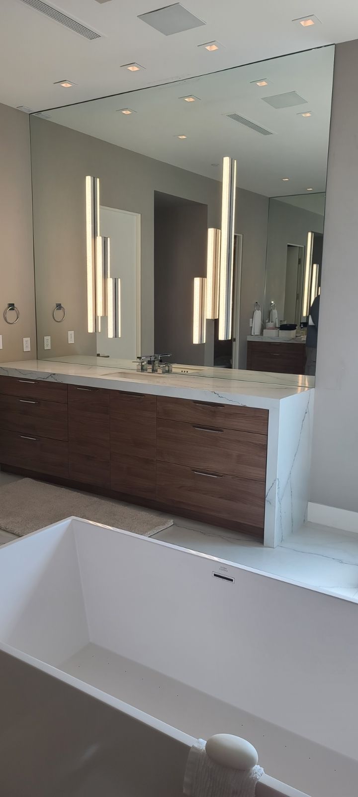 A bathroom with a large mirror and a bathtub.