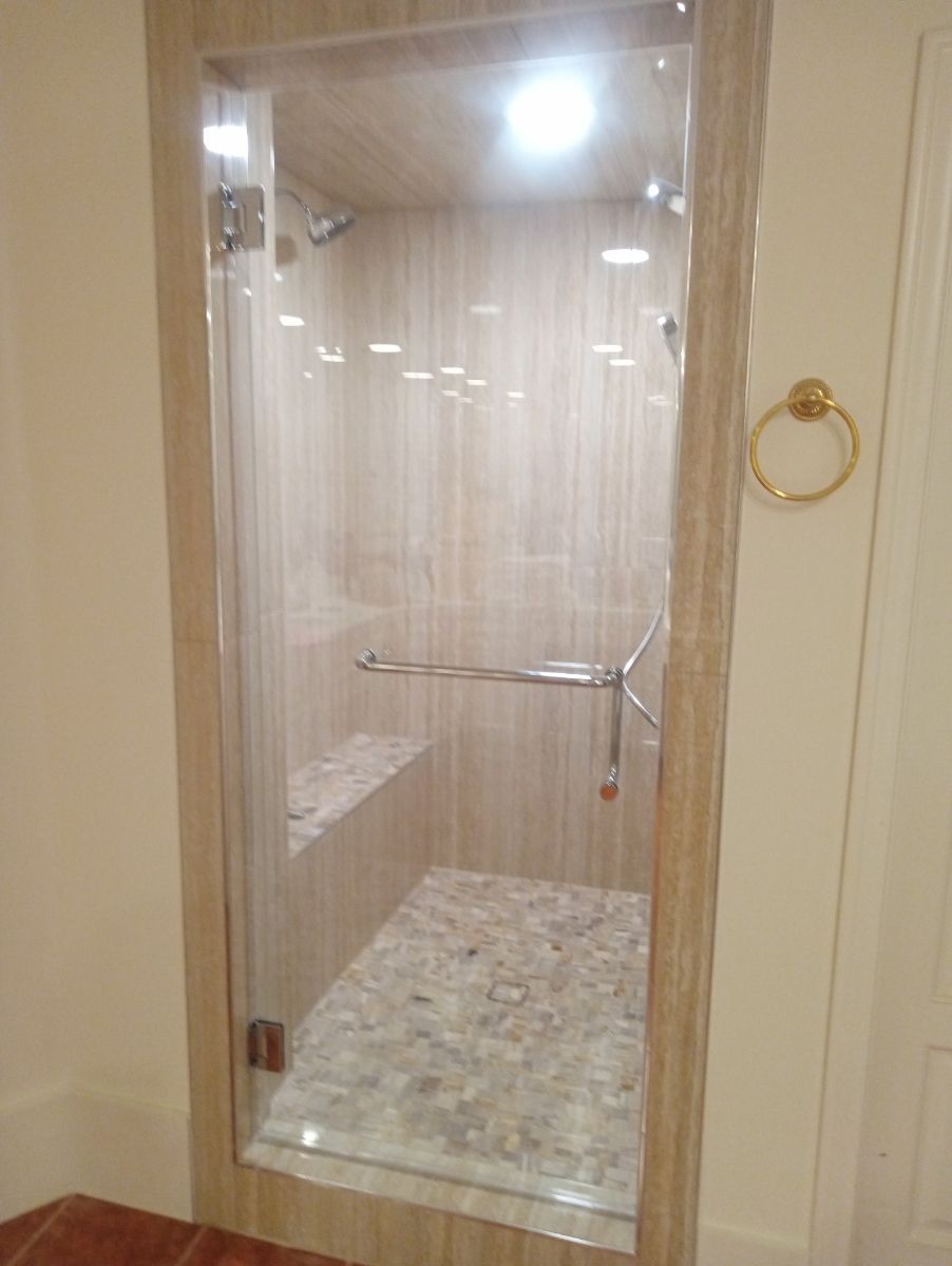 A bathroom with a walk in shower with a glass door.