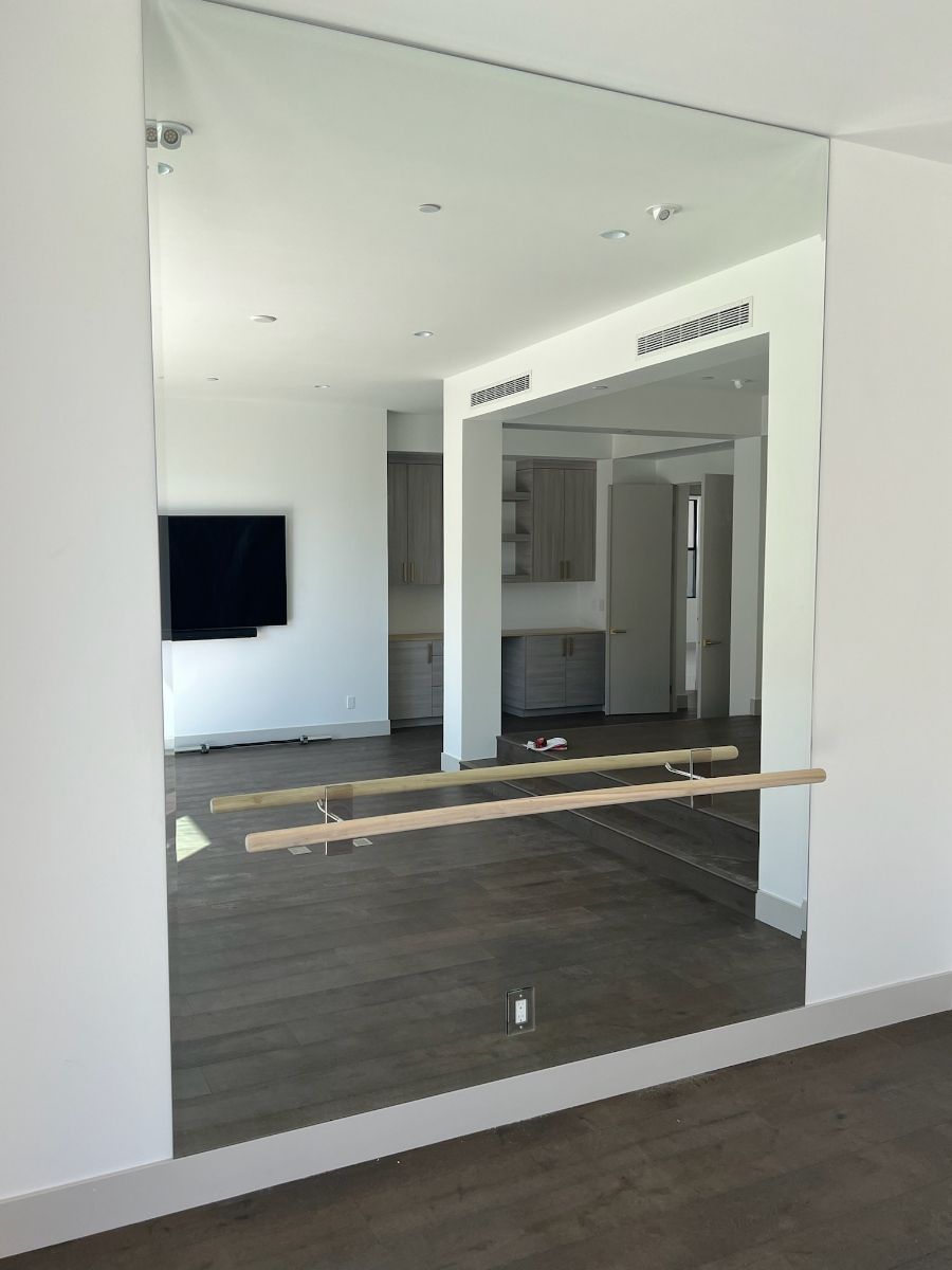 A large mirror with a wooden bar in a room.