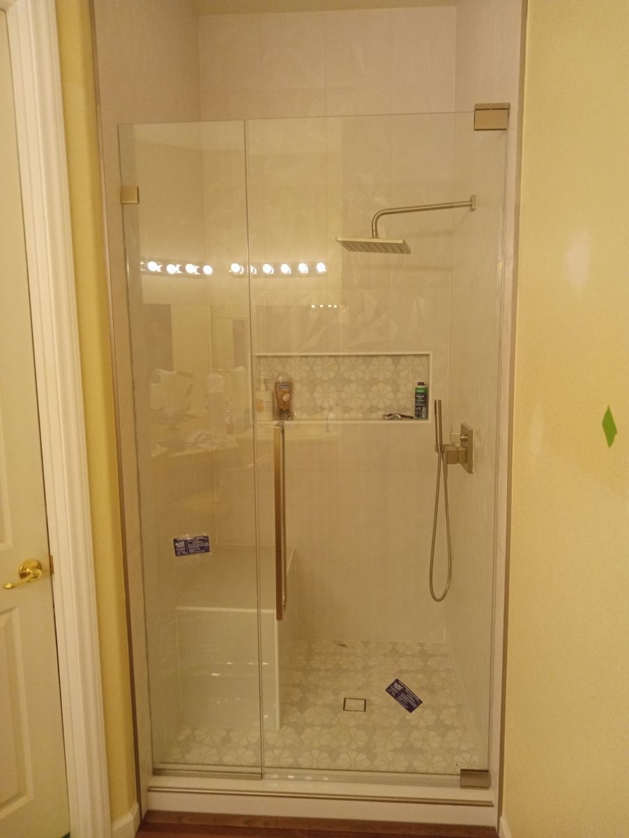 A bathroom with a glass shower door and a shower head.