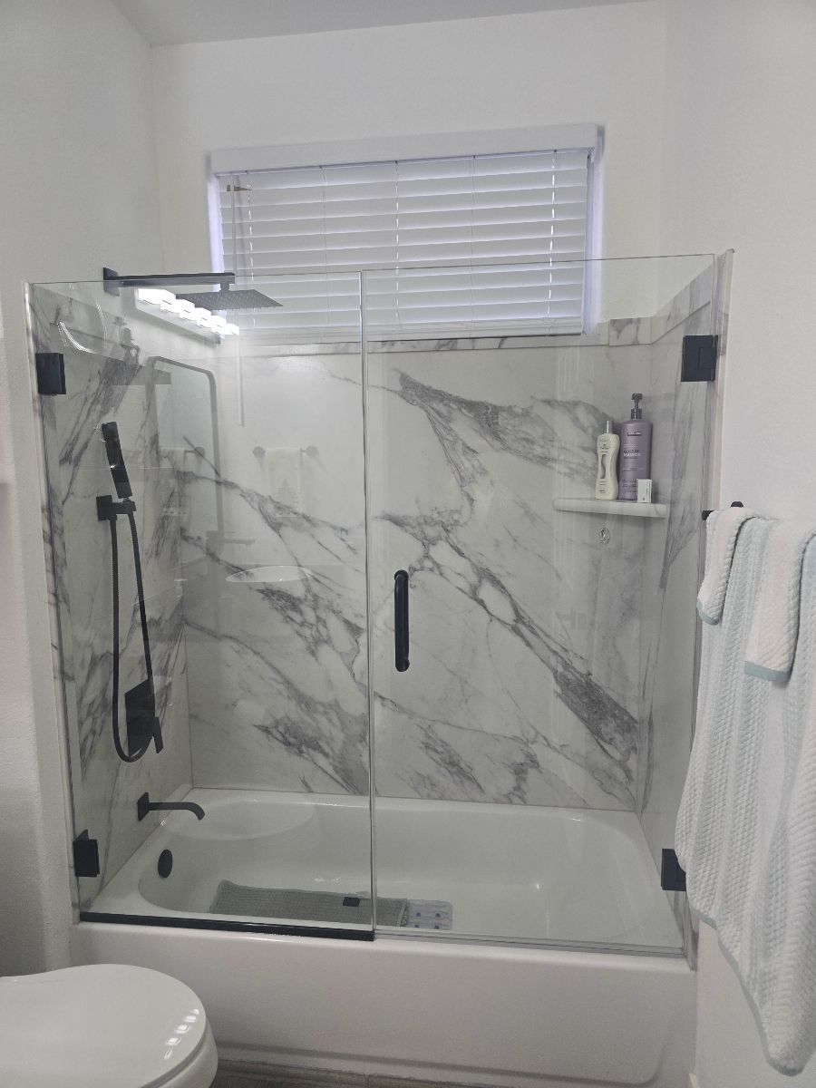 A bathroom with a bathtub , toilet , shower and marble walls.