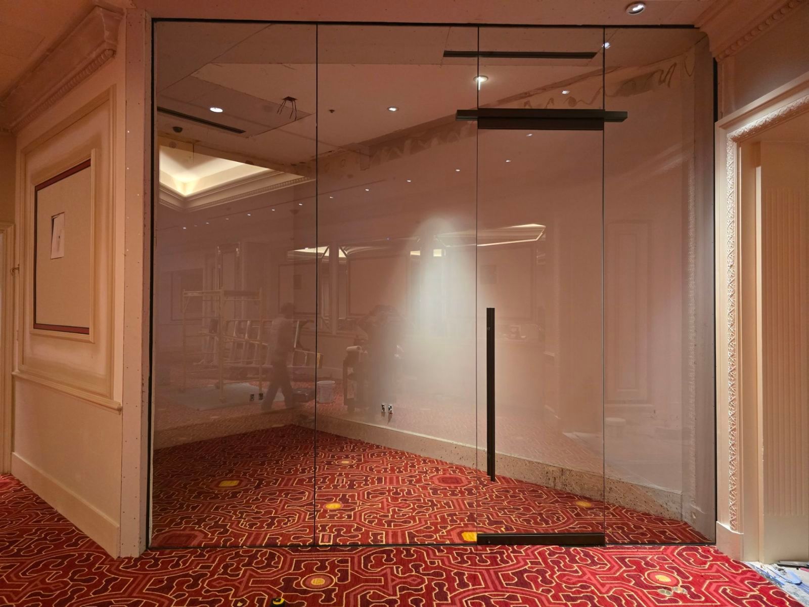 A hallway with a glass door and a red carpet.