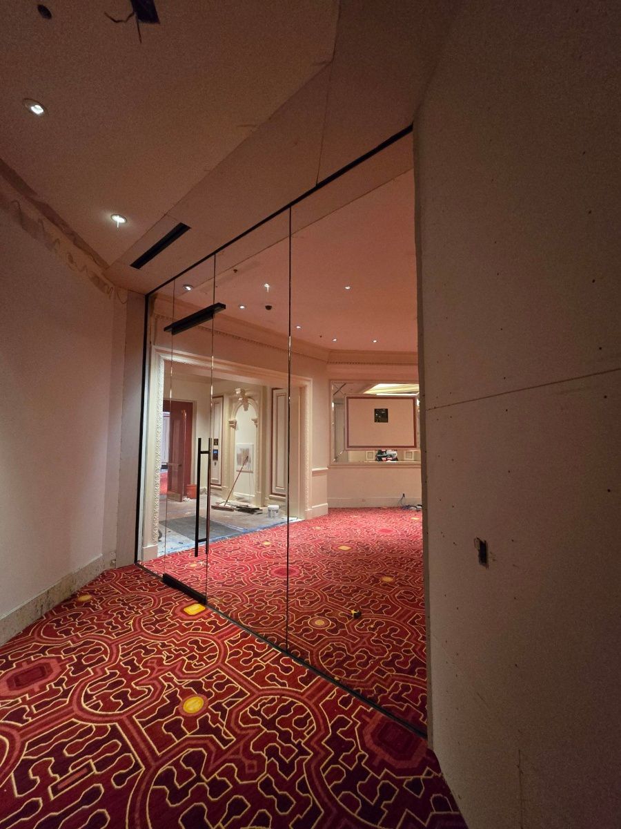 A hallway with a red carpet and a glass door