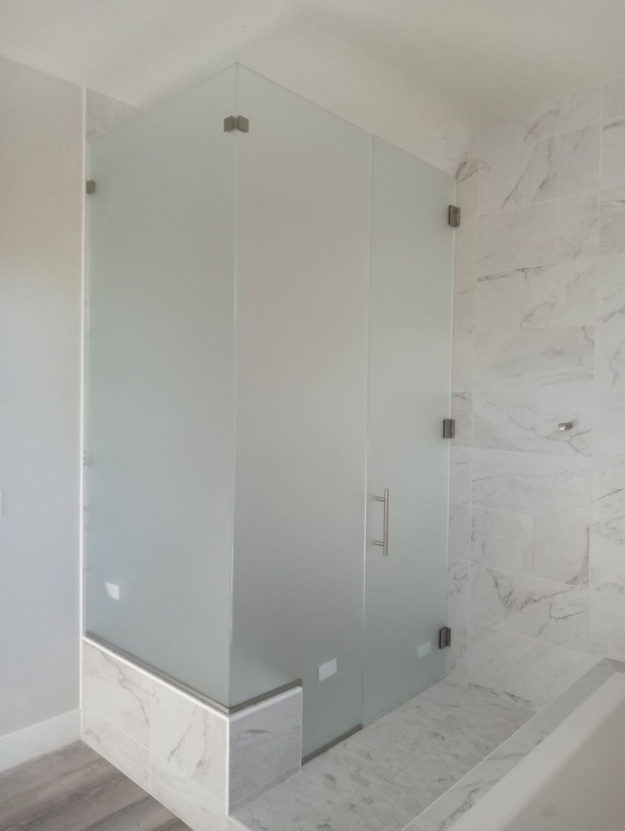 A bathroom with a glass shower door and a bathtub.