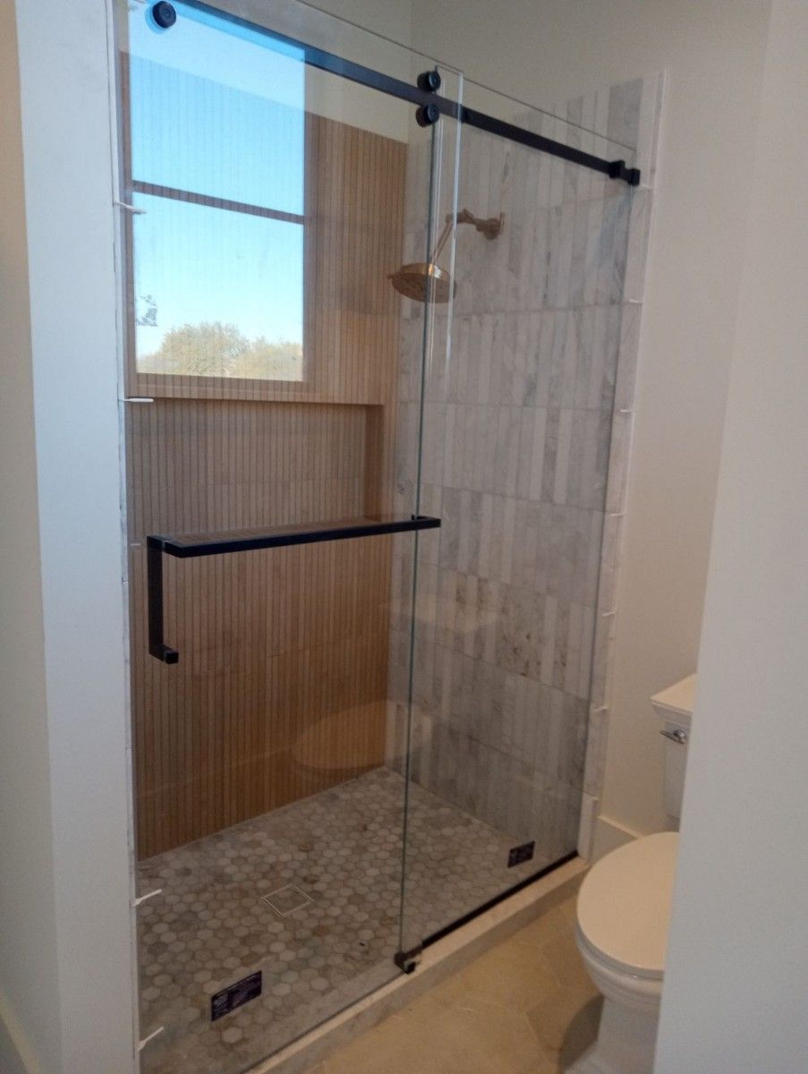 A bathroom with a sliding glass shower door and a toilet.