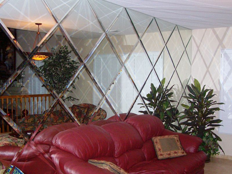 A living room with a red couch and a mirrored wall