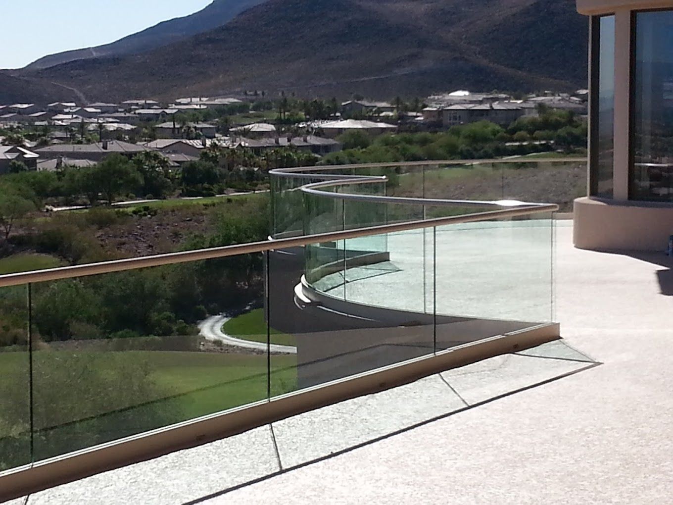 A balcony with a glass railing and mountains in the background