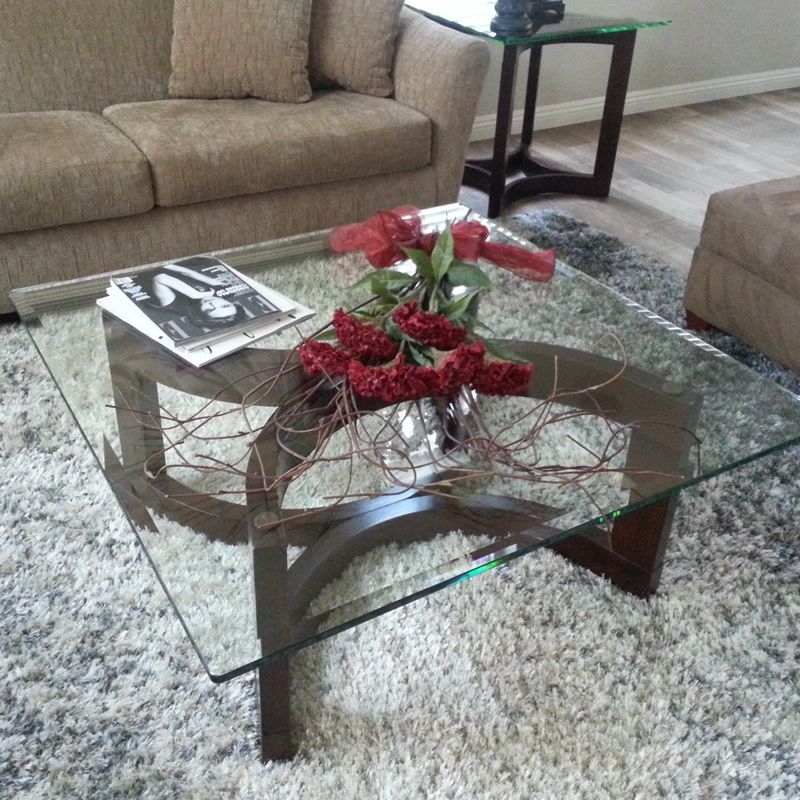 A glass coffee table with a vase of red roses on it