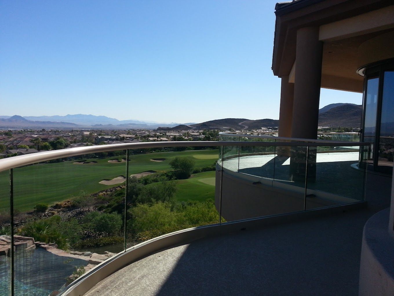 A balcony with a view of a golf course and mountains