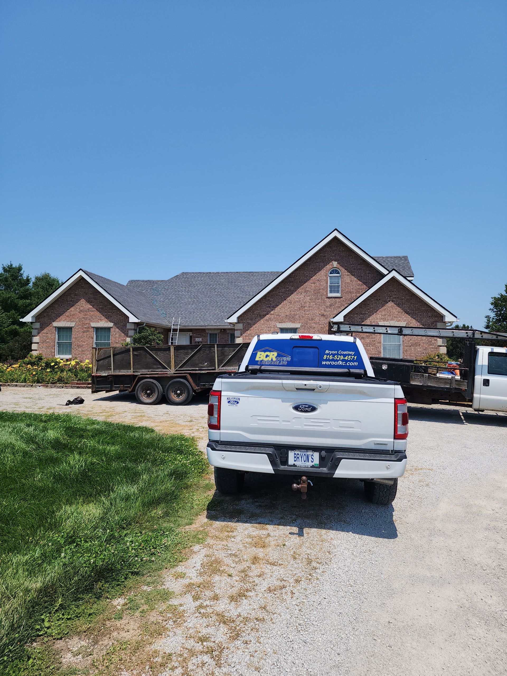 A white truck is parked in front of a large brick house.