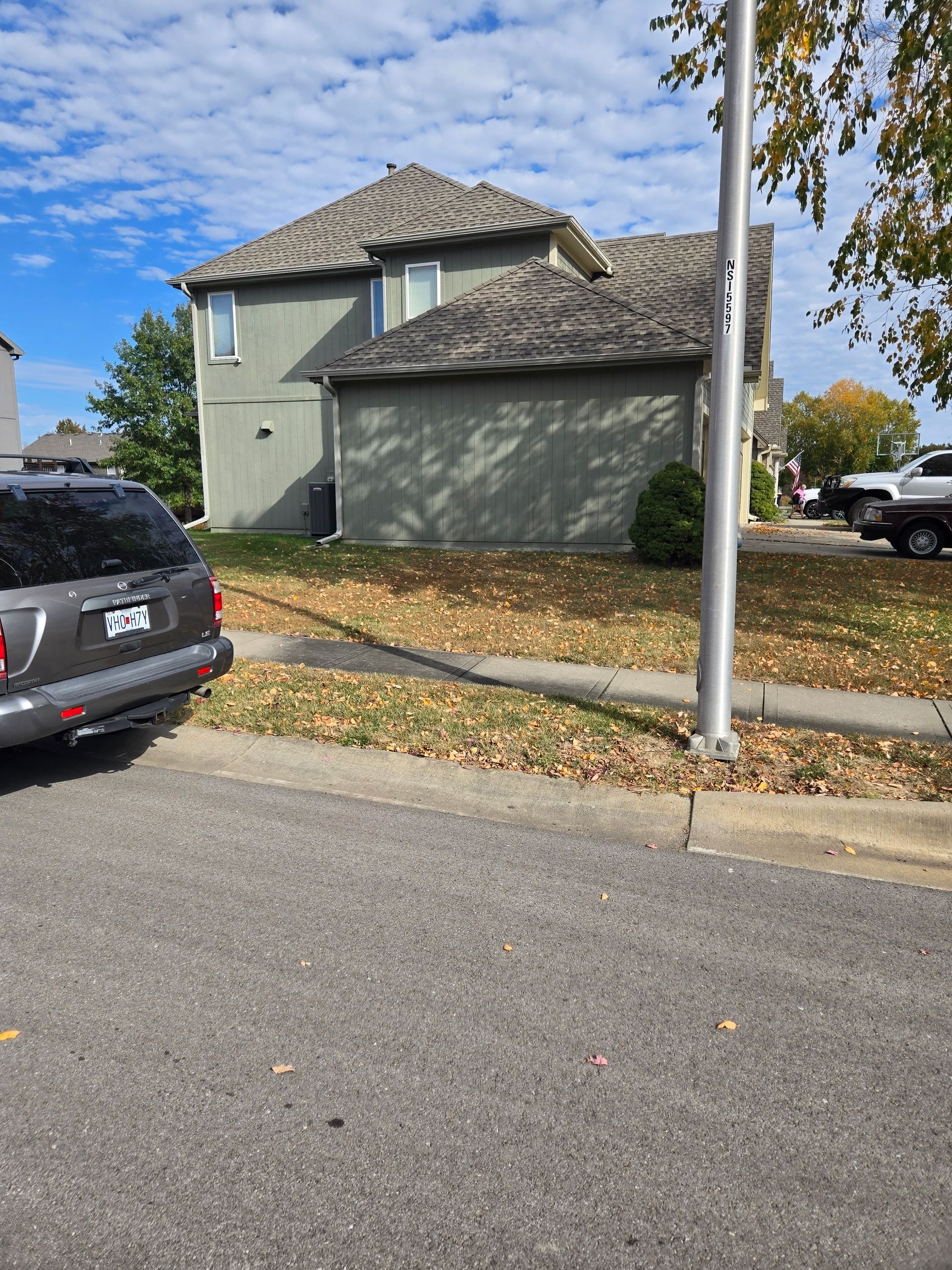 A car is parked on the side of the road in front of a house.