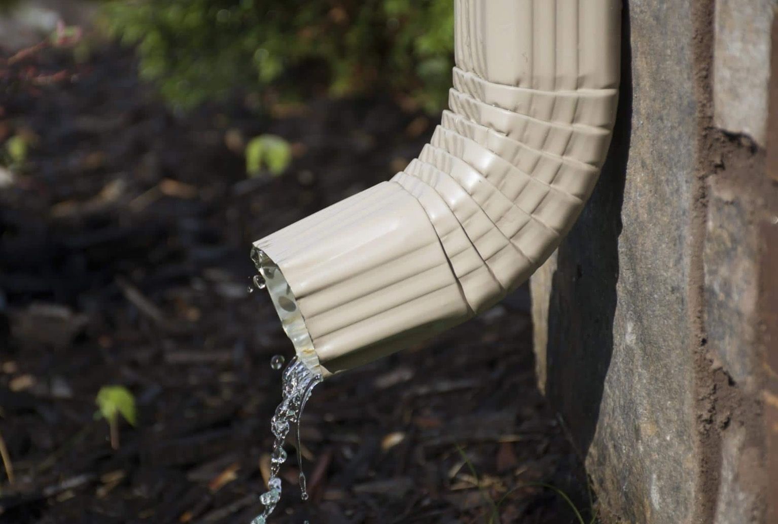 A white porch post with a black drainpipe attached to it.