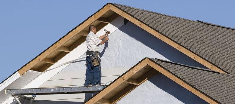 A man is working on the roof of a house.