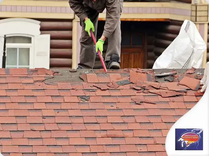 A man is standing on top of a roof with a broom.