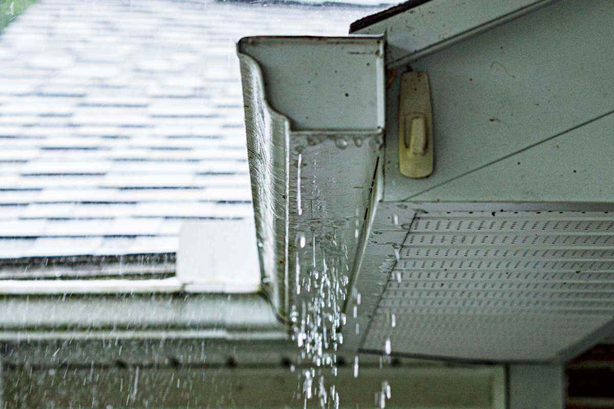 A gutter is leaking water from the roof of a house.