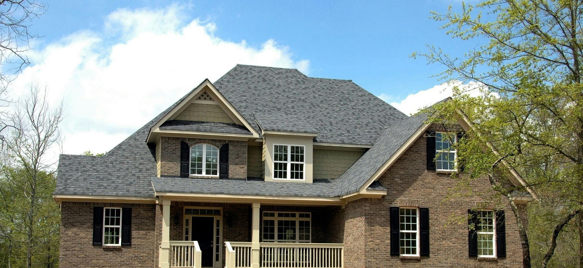 A large brick house with a gray roof and black shutters