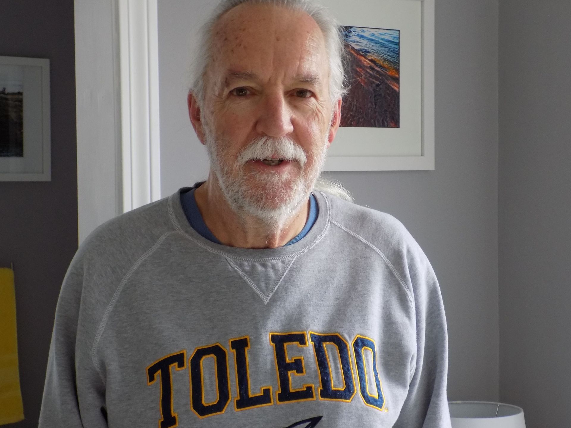 A man with a beard is wearing a toledo sweatshirt.