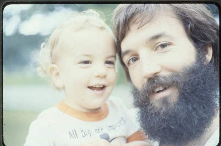 A man with a beard is holding a child in his arms.