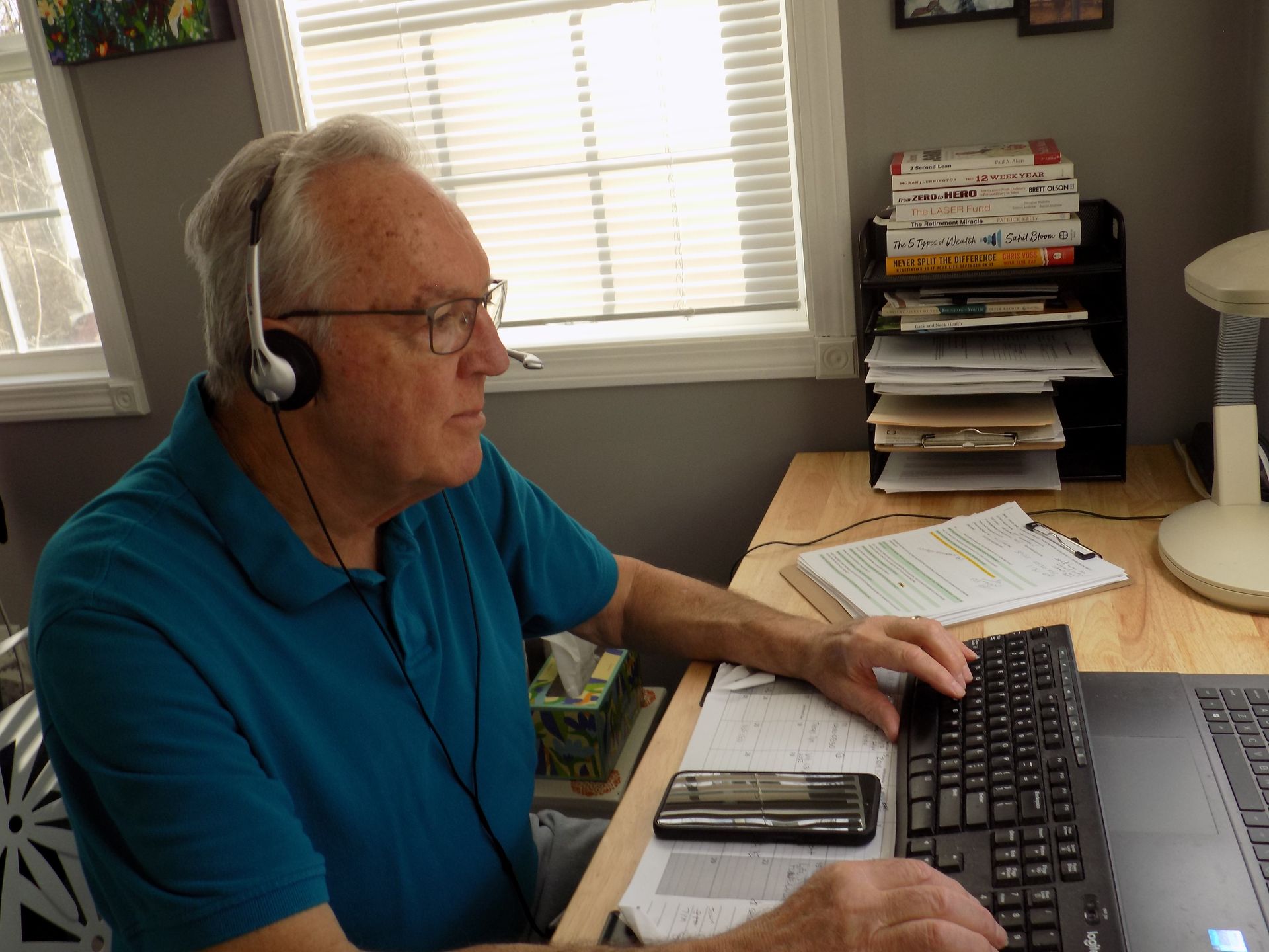 A man wearing headphones is typing on a computer keyboard.