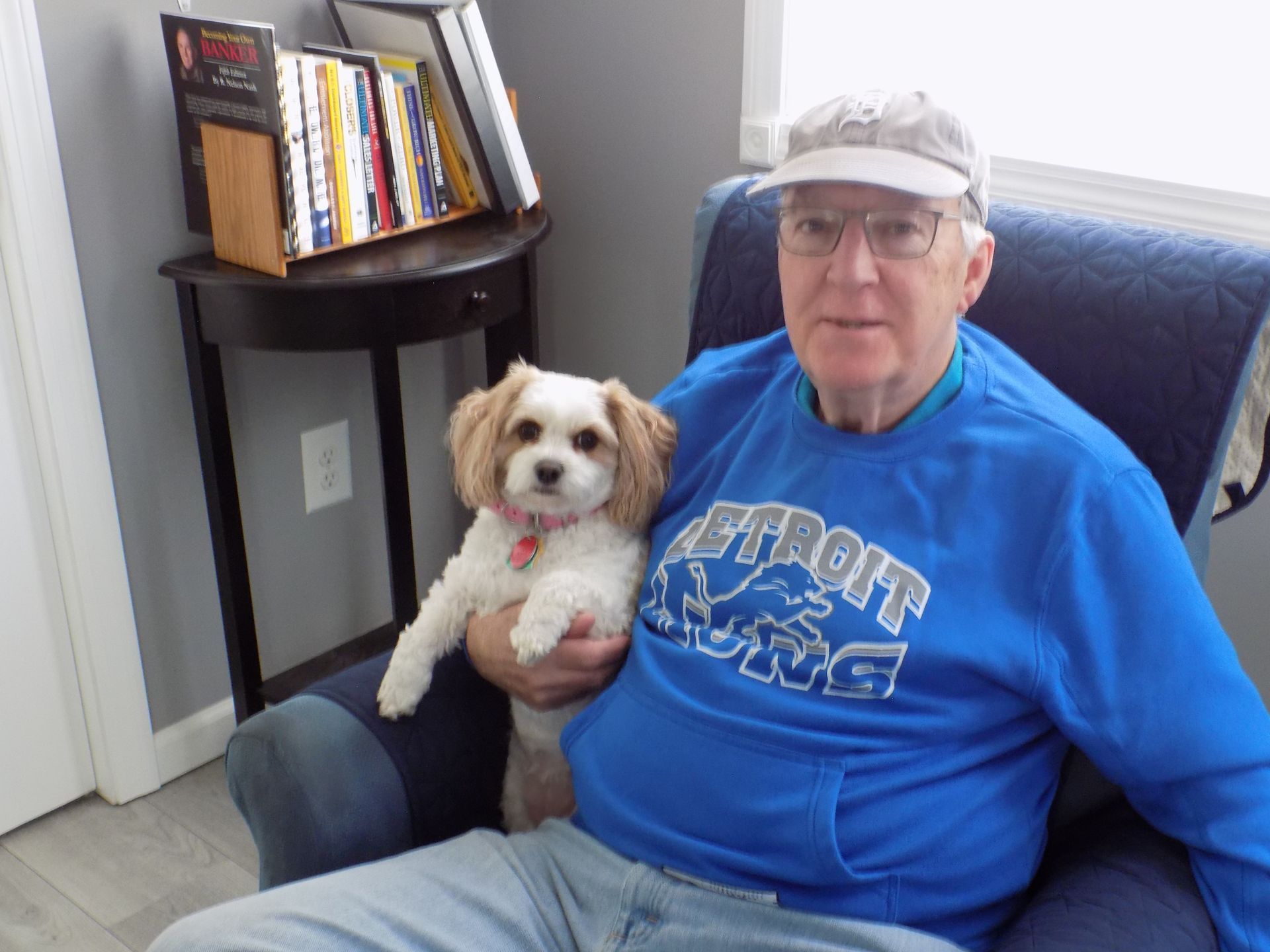 A man in a detroit lions shirt is holding a small dog
