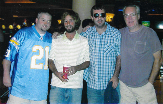 Four men are posing for a picture with one wearing a jersey with the number 21 on it
