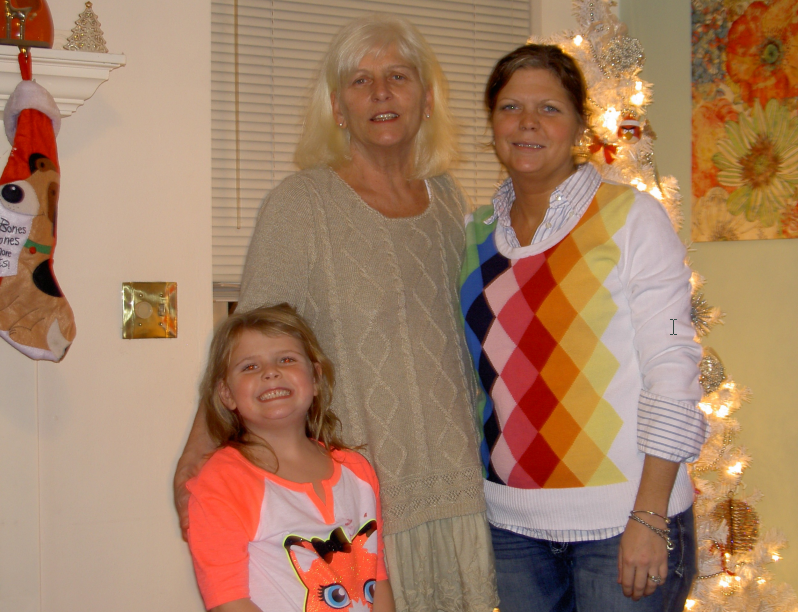 Three women are posing for a picture in front of a christmas tree