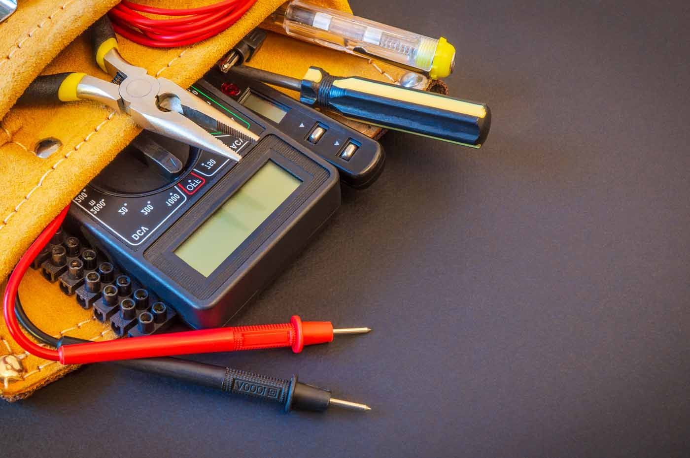 A tool belt filled with electrical tools and a multimeter.