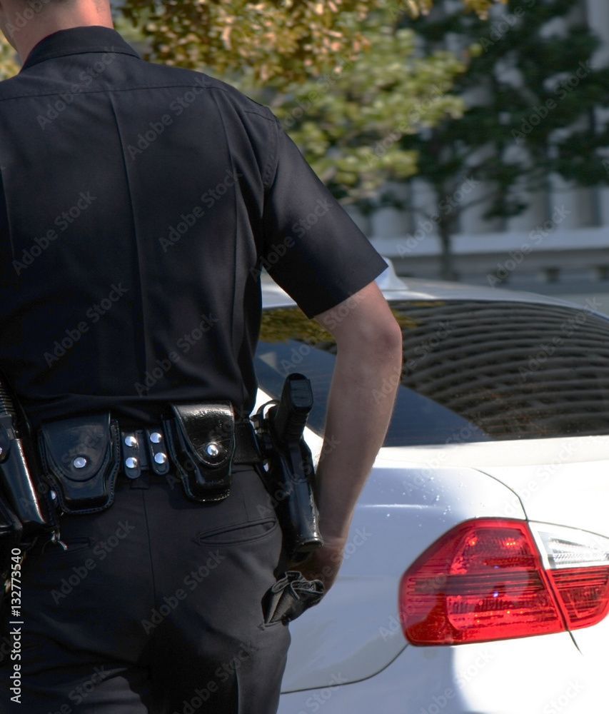 A police officer is standing next to a white car
