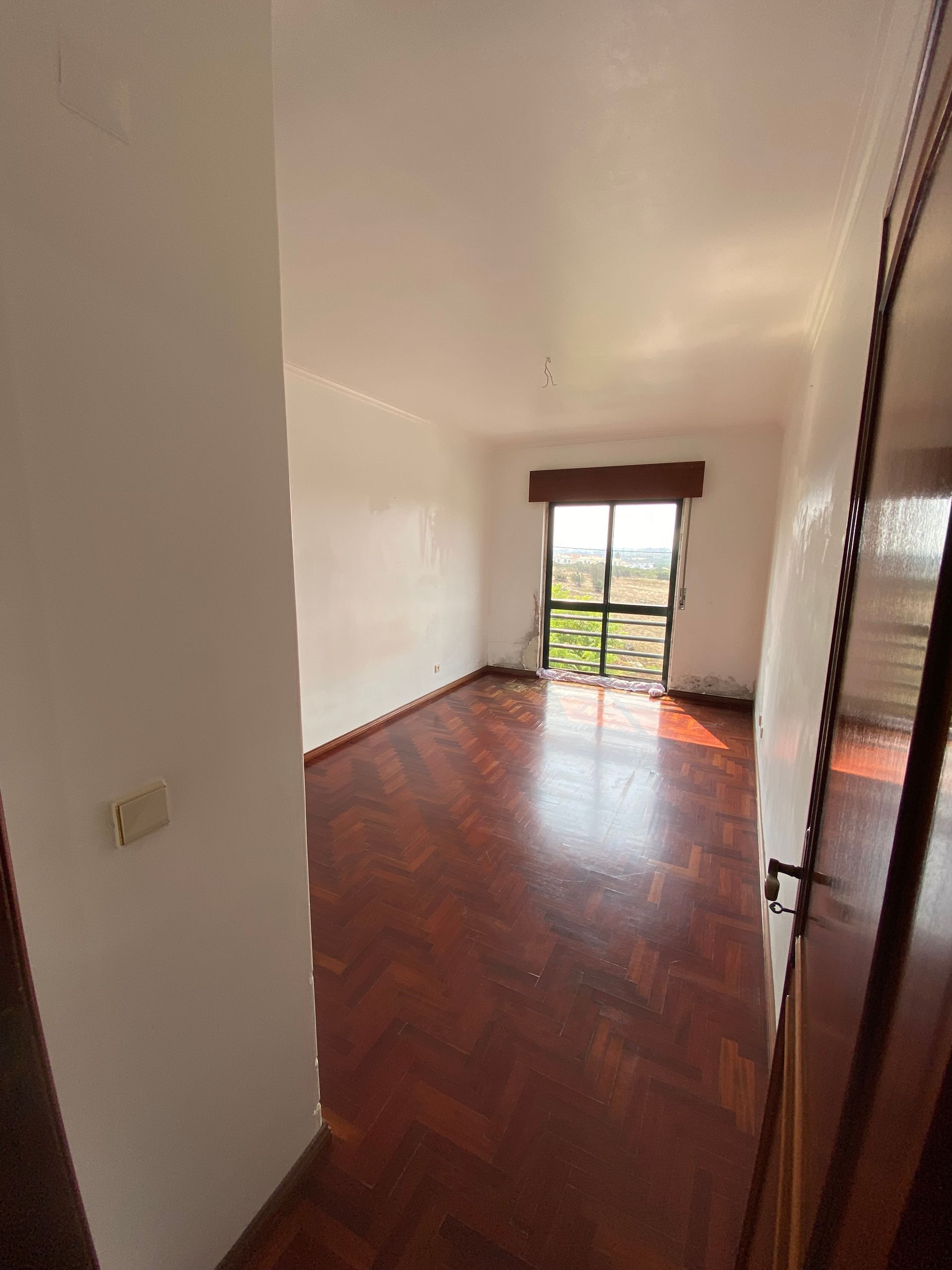 Uma sala vazia com piso de madeira e uma grande janela.