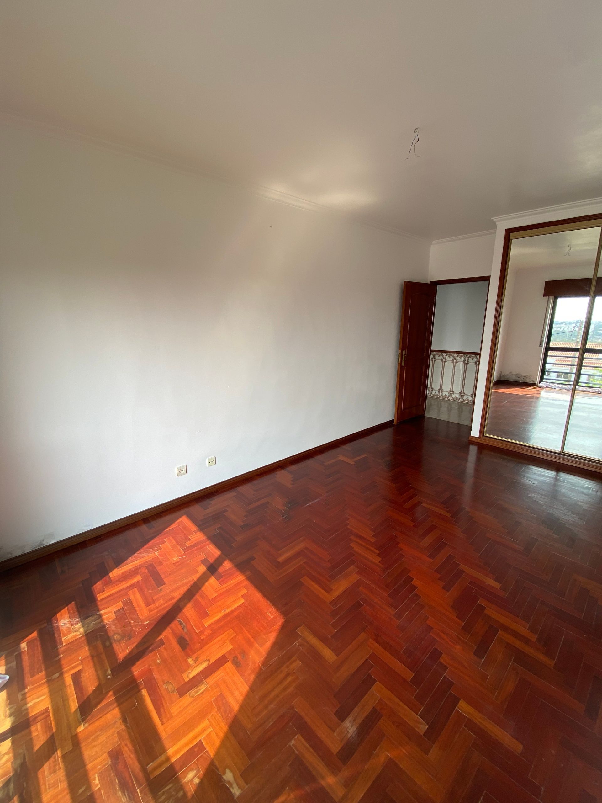 Uma sala vazia com piso de madeira e um grande espelho