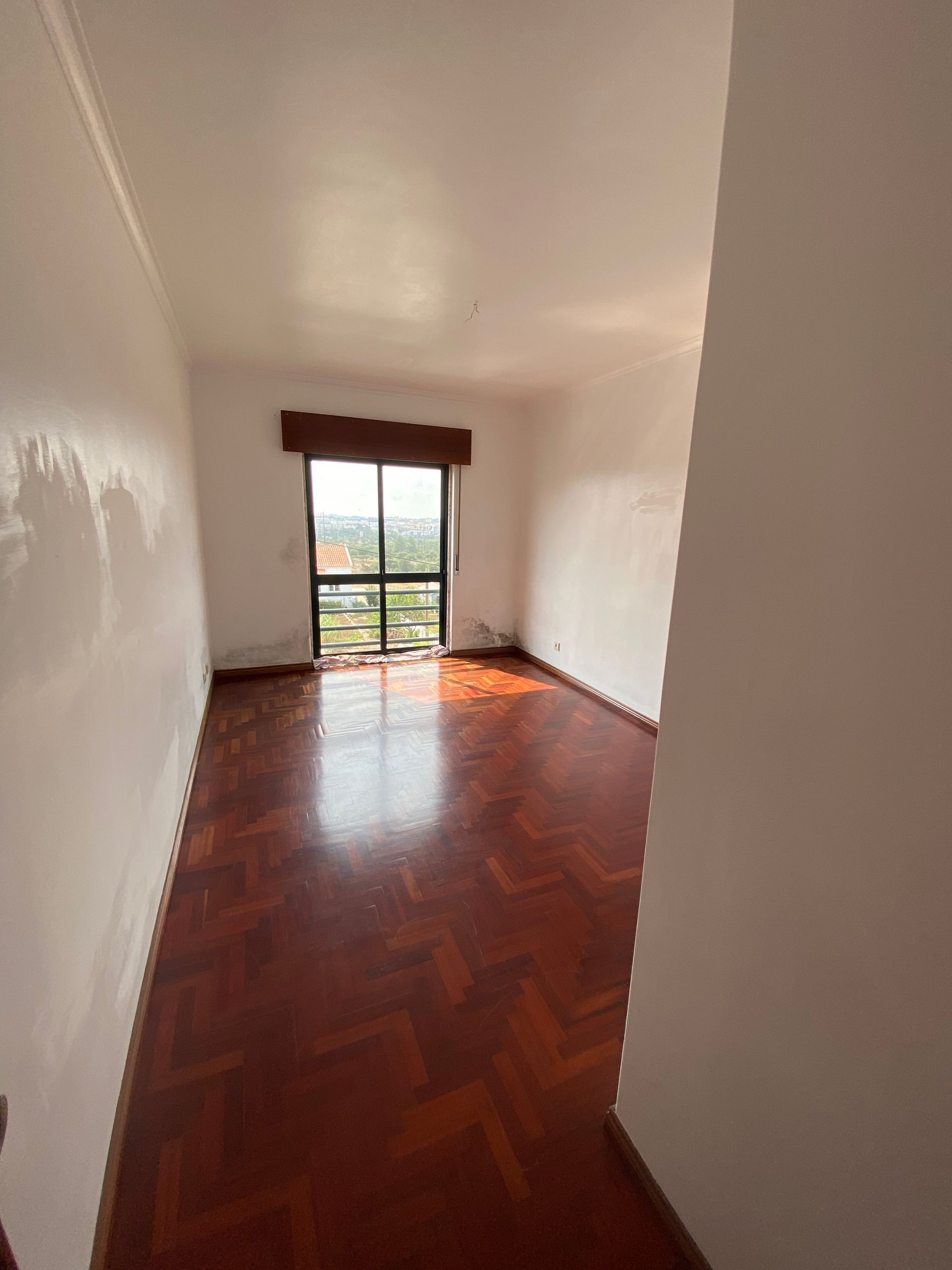 Uma sala de estar com piso de madeira e uma grande janela.