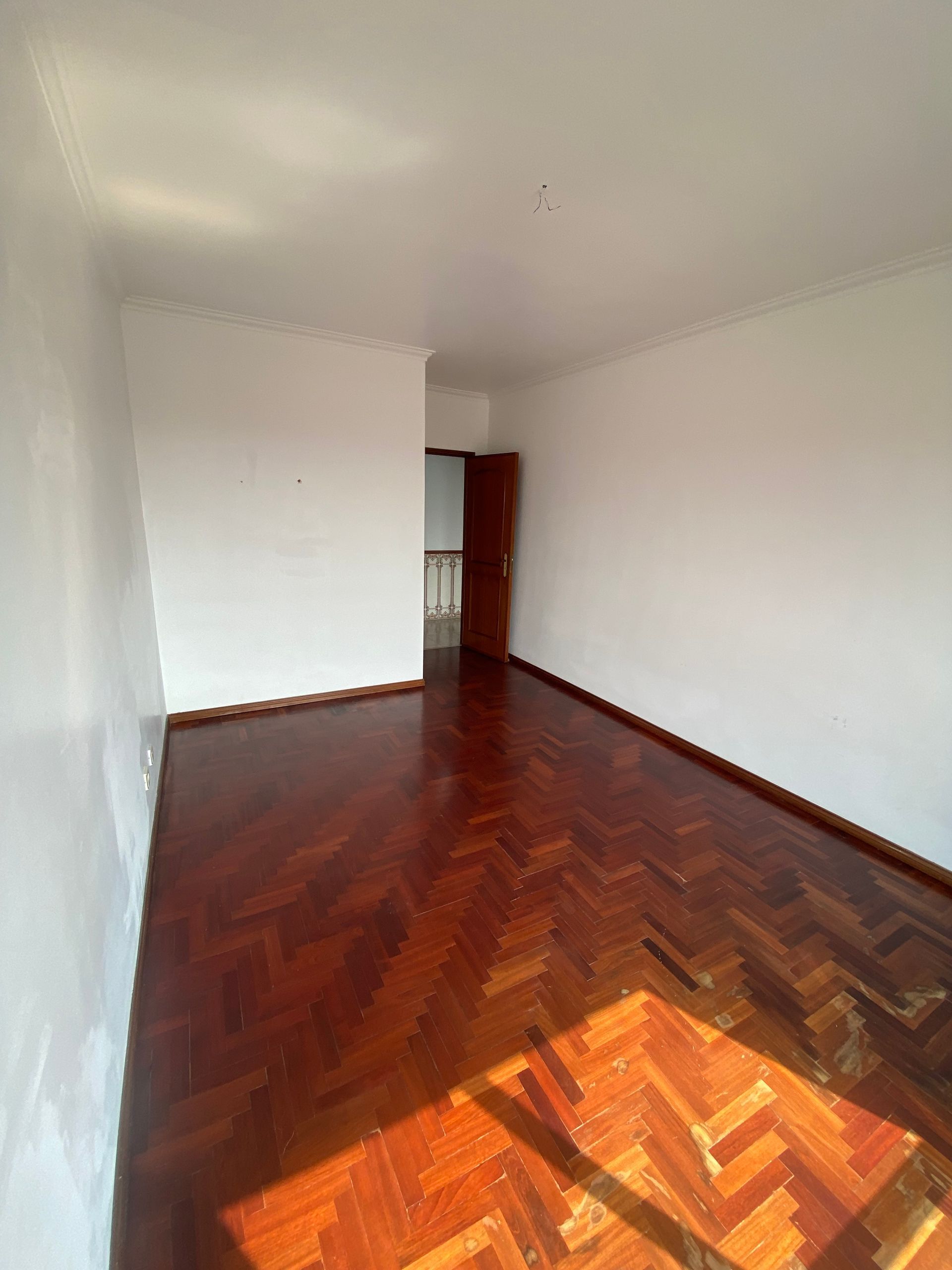 Uma sala vazia com piso de madeira e paredes brancas.