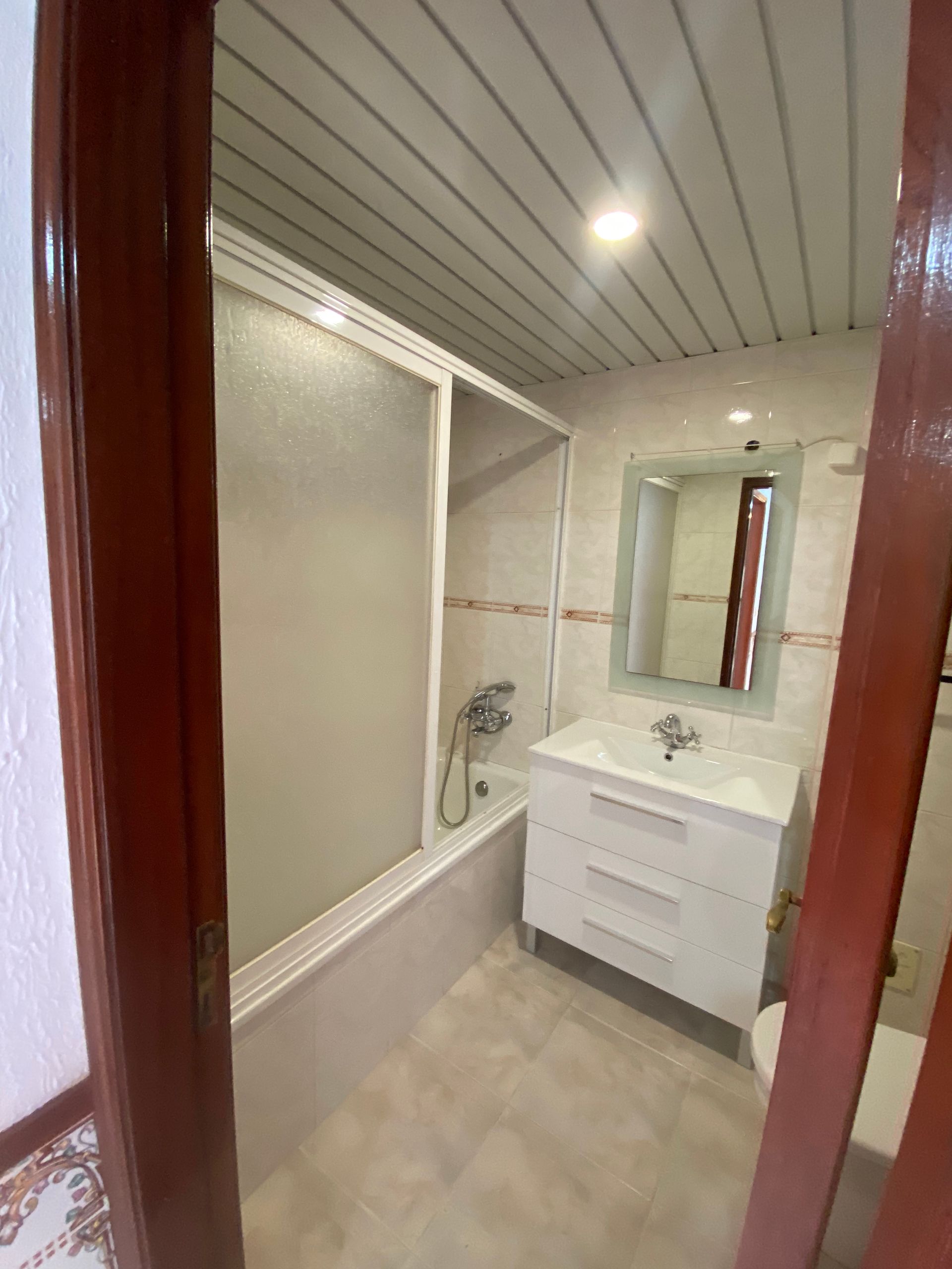 Um banheiro com banheira, pia, espelho e box de chuveiro.