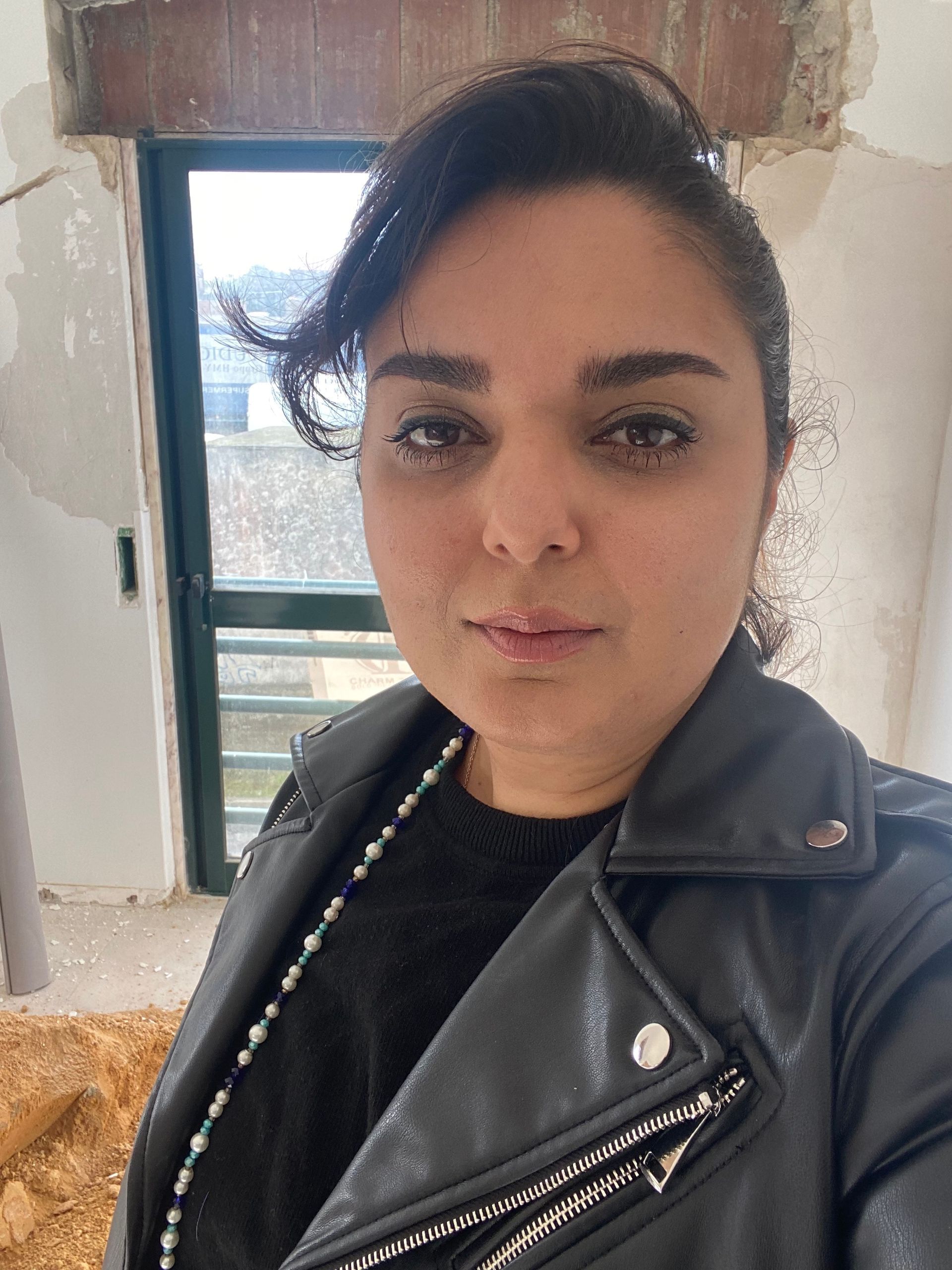 Uma mulher vestindo uma jaqueta de couro preta está tirando uma selfie.